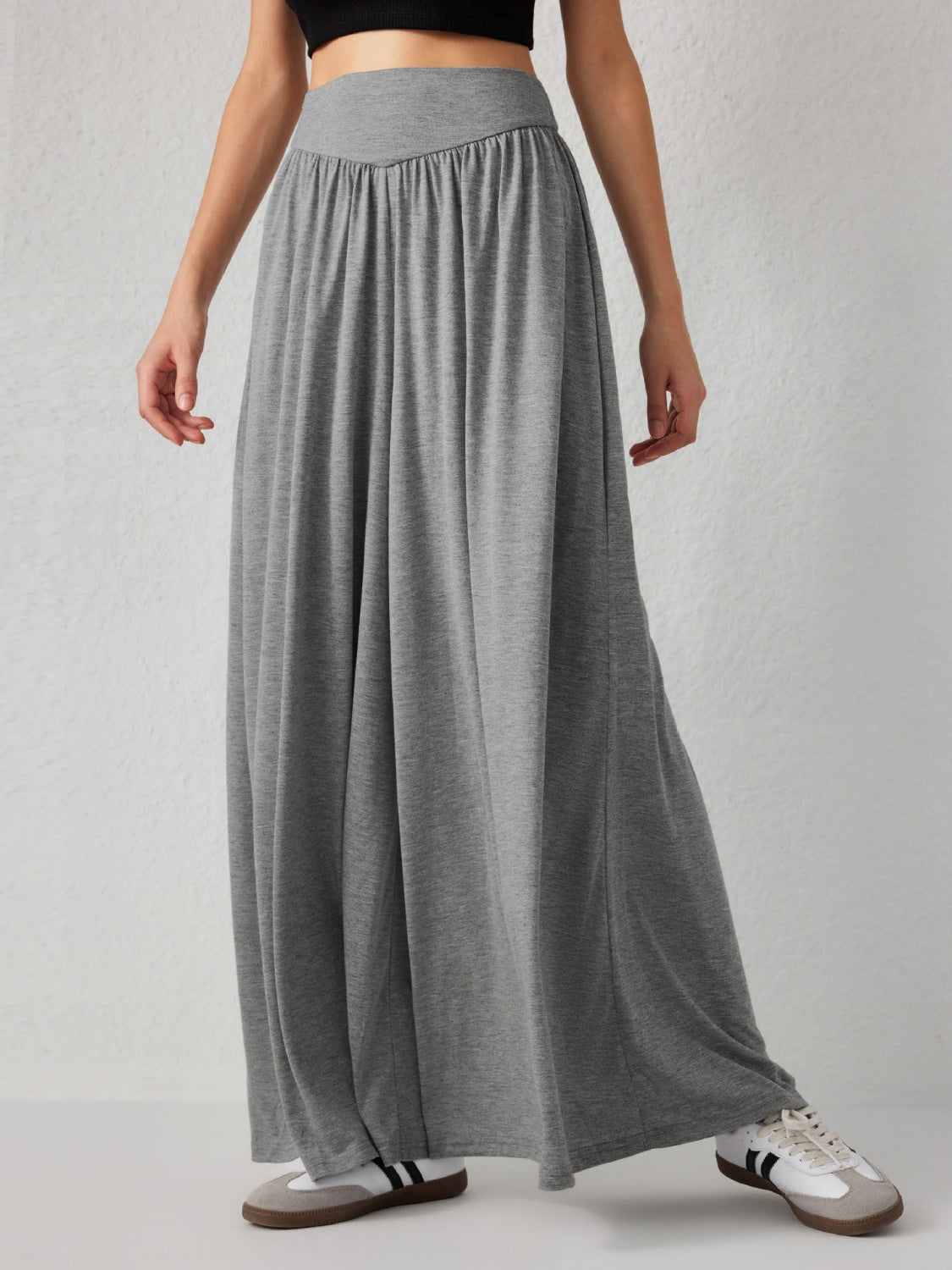 Grey jersey wide-leg trousers with a draped V-waistband and flowy silhouette.