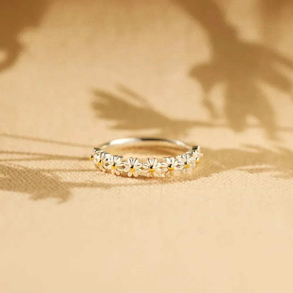 Daisy chain silver band ring with white enamel flowers and yellow centers.