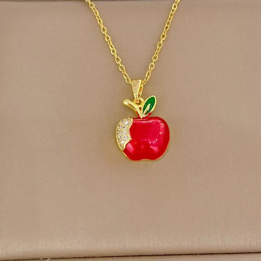 Gold-plated necklace with a red apple pendant accented with clear stones and green leaf detail.
