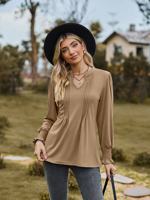 Khaki long sleeve blouse with V-neck, pleated yoke, and shirred cuffs.