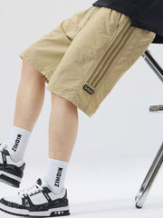 Khaki casual drawstring shorts with sporty side stripes and a number patch.