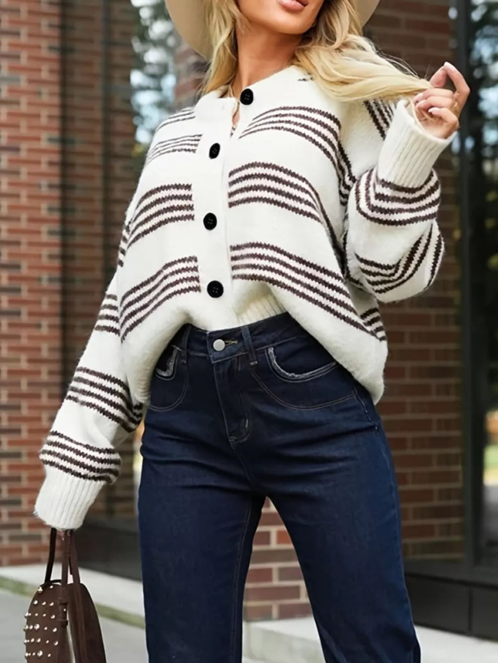 Chunky striped knit cardigan with black buttons and ribbed cuffs, worn open over dark wash jeans.