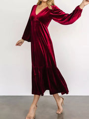Burgundy velvet midi dress with V-neck, long sleeves, and tiered skirt.