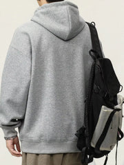 Gray cotton drawstring hoodie with a relaxed fit, worn with a backpack.