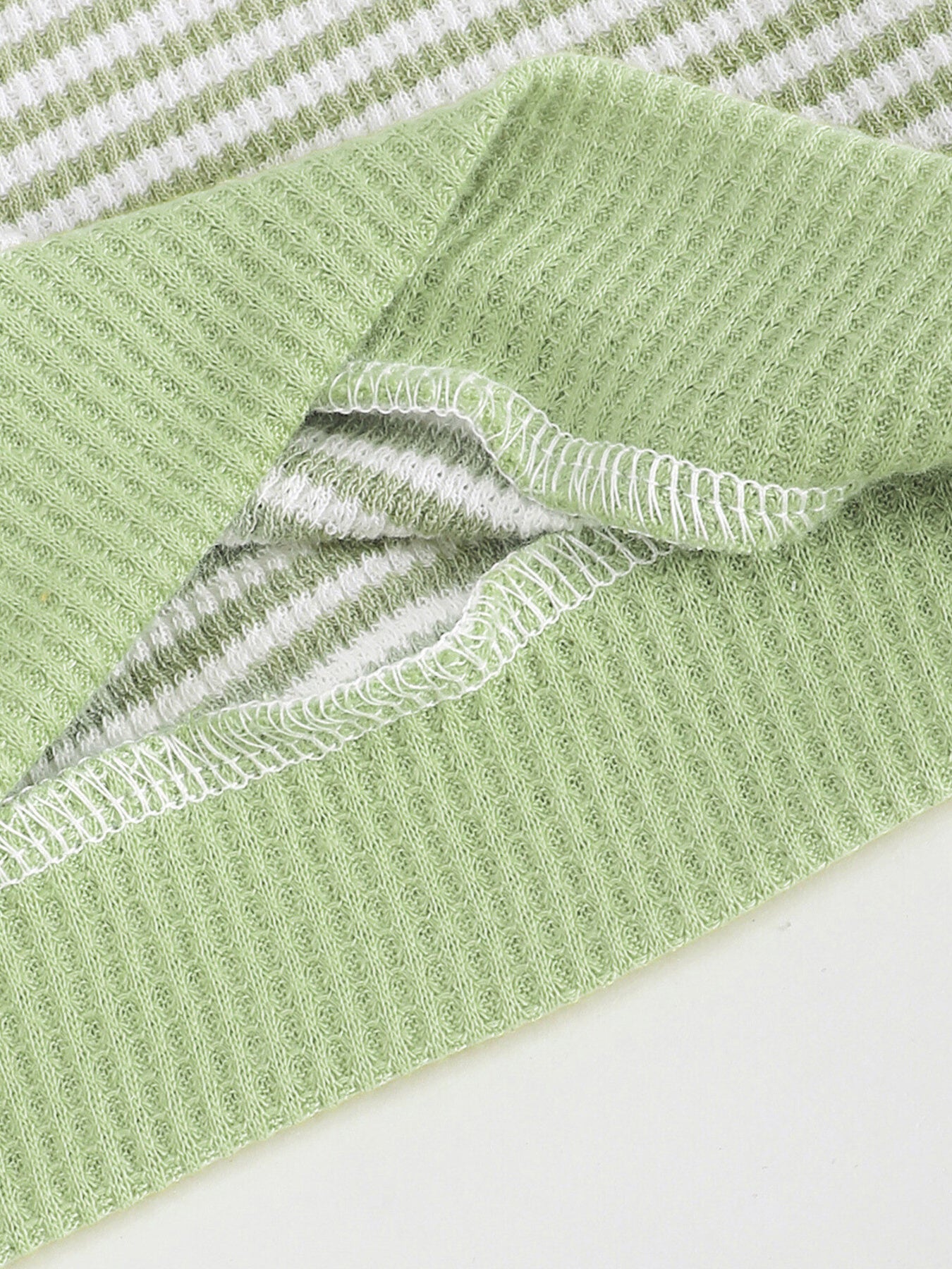 Green and white striped cotton polo shirt with waffle knit texture and white stitching detail.