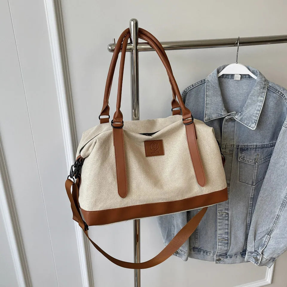 Canvas weekend holdall duffel bag with brown leather trim and straps, and a detachable shoulder strap.