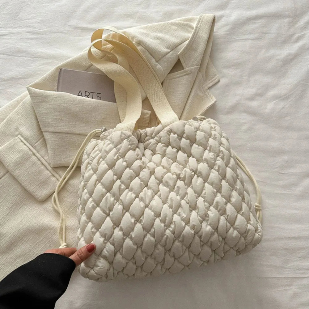 Ivory quilted drawstring carryall bag with textured pattern and dual straps.
