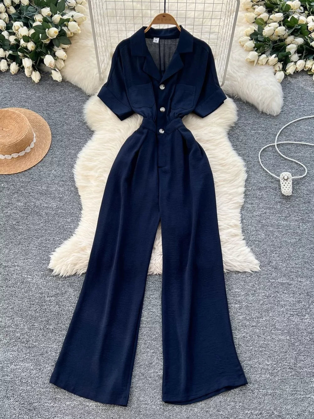 Navy belted wide-leg maternity jumpsuit with pockets and button front.