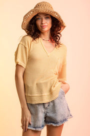 Yellow waffle knit v-neck top with short sleeves and a chest pocket.