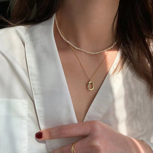 Gold geometric pendant necklace set with pearl strand necklace.