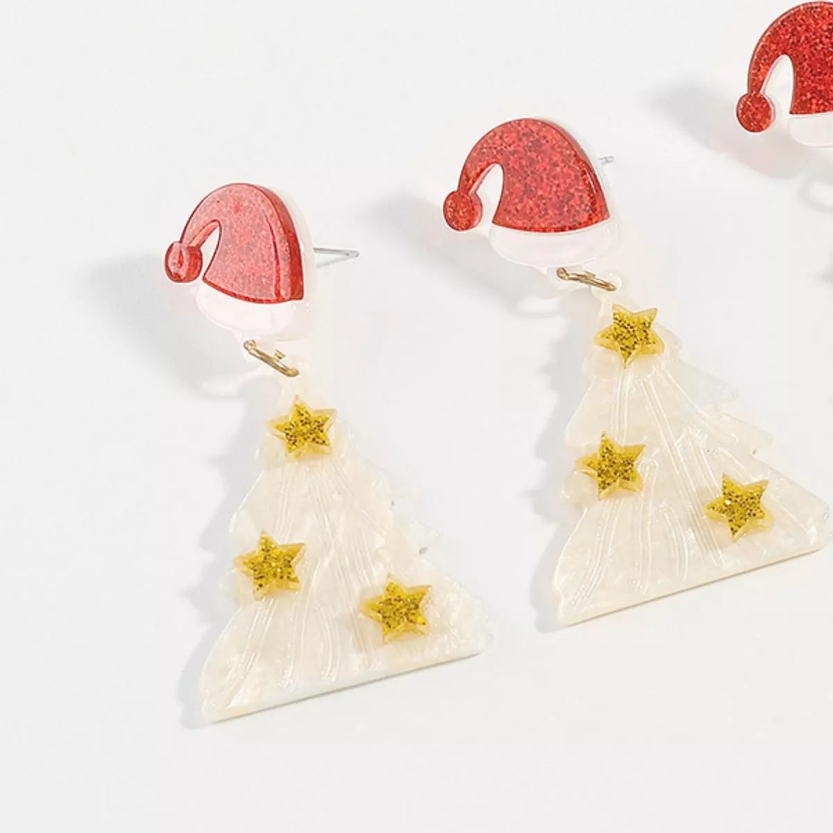 White acrylic Christmas tree dangle earrings with gold stars and Santa hats.