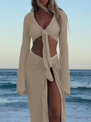 Beige openwork acrylic sweater set with tie front crop top and high slit skirt.