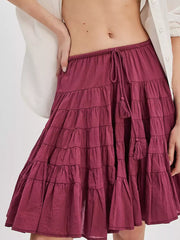 Tiered drawstring mini skirt in cerise with tassel detail and ruffled tiers.