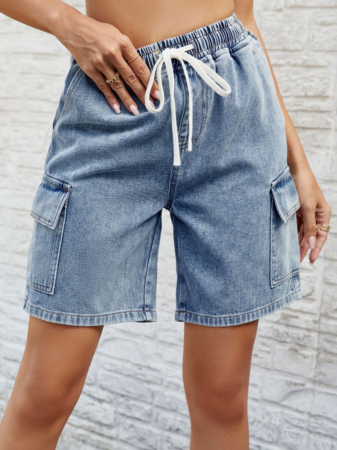 Denim cargo shorts in dusty blue with drawstring waist and side pockets.