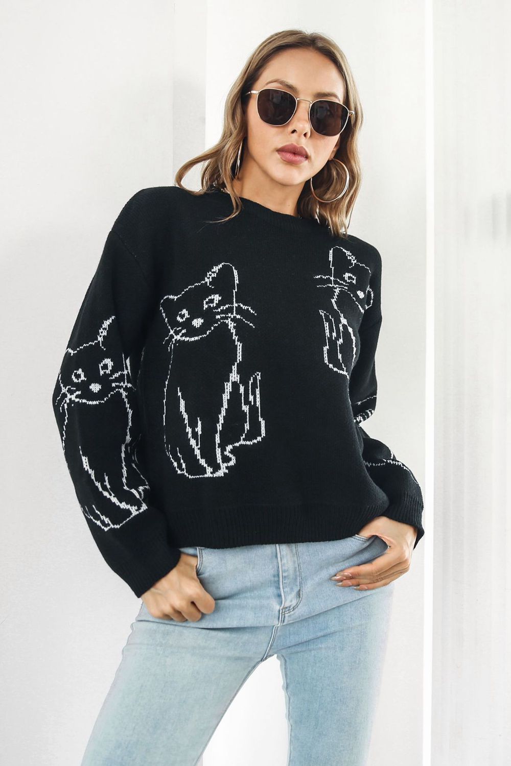 Black acrylic sweater with white cat intarsia motif, crew neck, long sleeves.