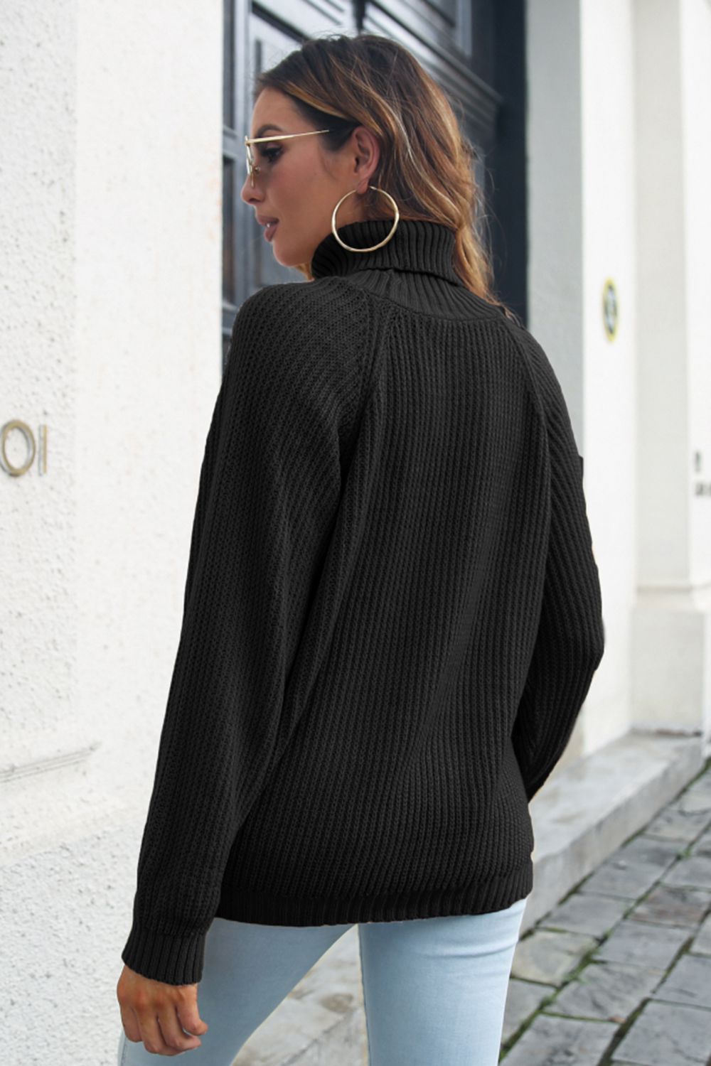 Black ribbed turtleneck sweater with raglan sleeves and a relaxed fit.