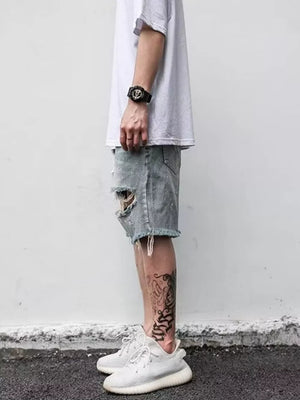 Men's light blue distressed denim shorts with raw hem and rips.
