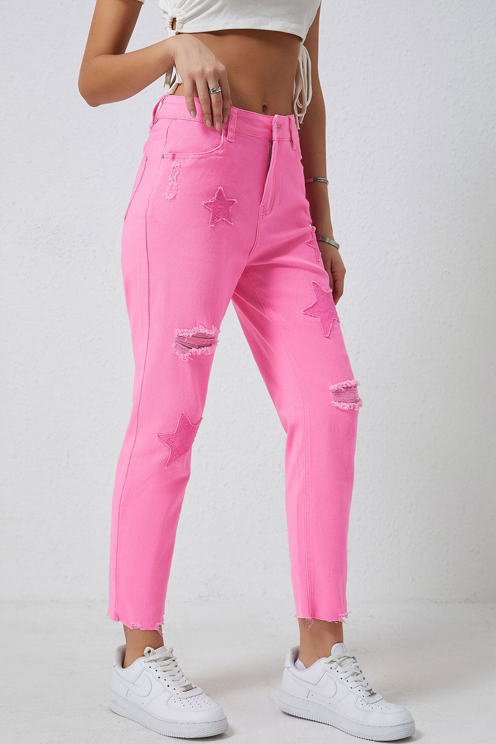 Pink denim jeans with star patches and distressed rips, frayed hem