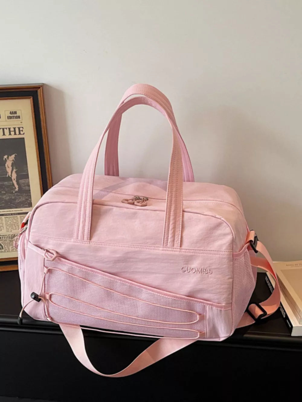 Pink nylon travel organizer bag with bungee cord detail and adjustable strap.