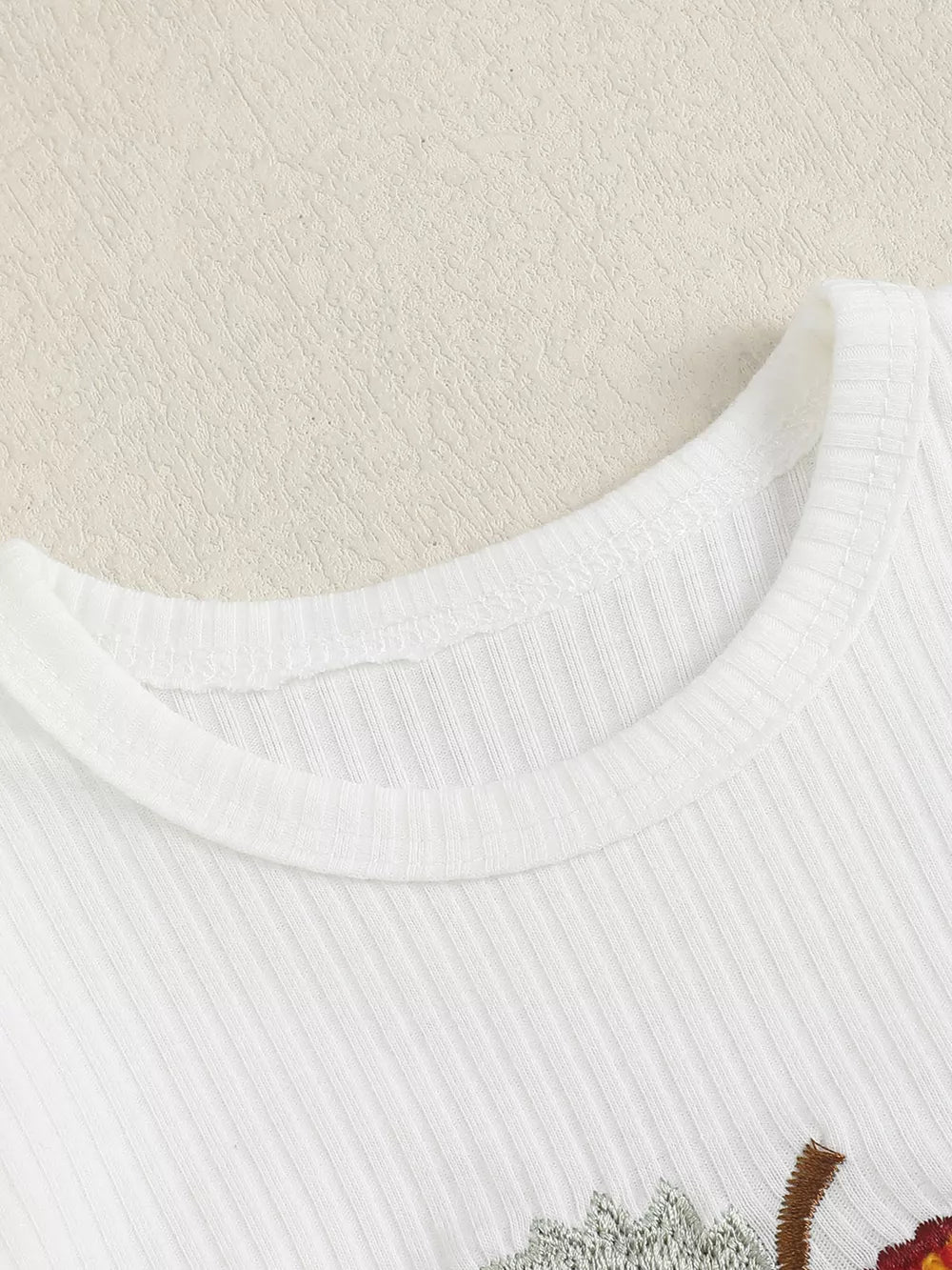 White ribbed cotton baby bodysuit with apple embroidery detail.