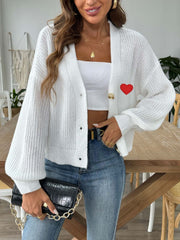 White knit cardigan with balloon sleeves and red heart appliqué detail.