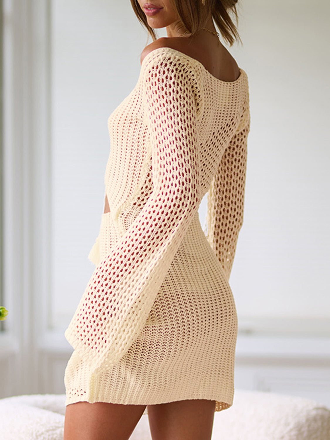 Cream crochet lace-up cutout mini dress with long sleeves and open knit detail.