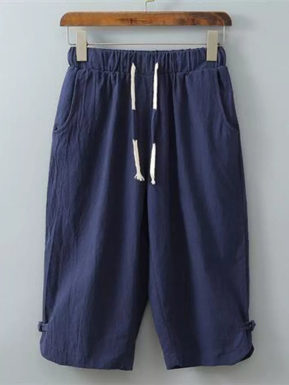 Navy blue cropped sweatpants with drawstring and side pockets.