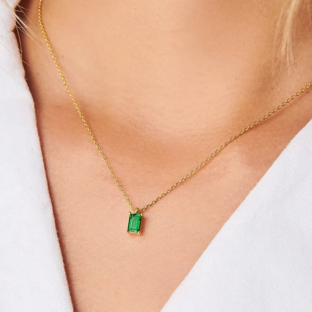 18K gold necklace with a single emerald-cut green gemstone pendant.