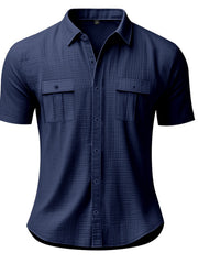 Navy blue short sleeve button-down shirt with two chest pockets and subtle texture.