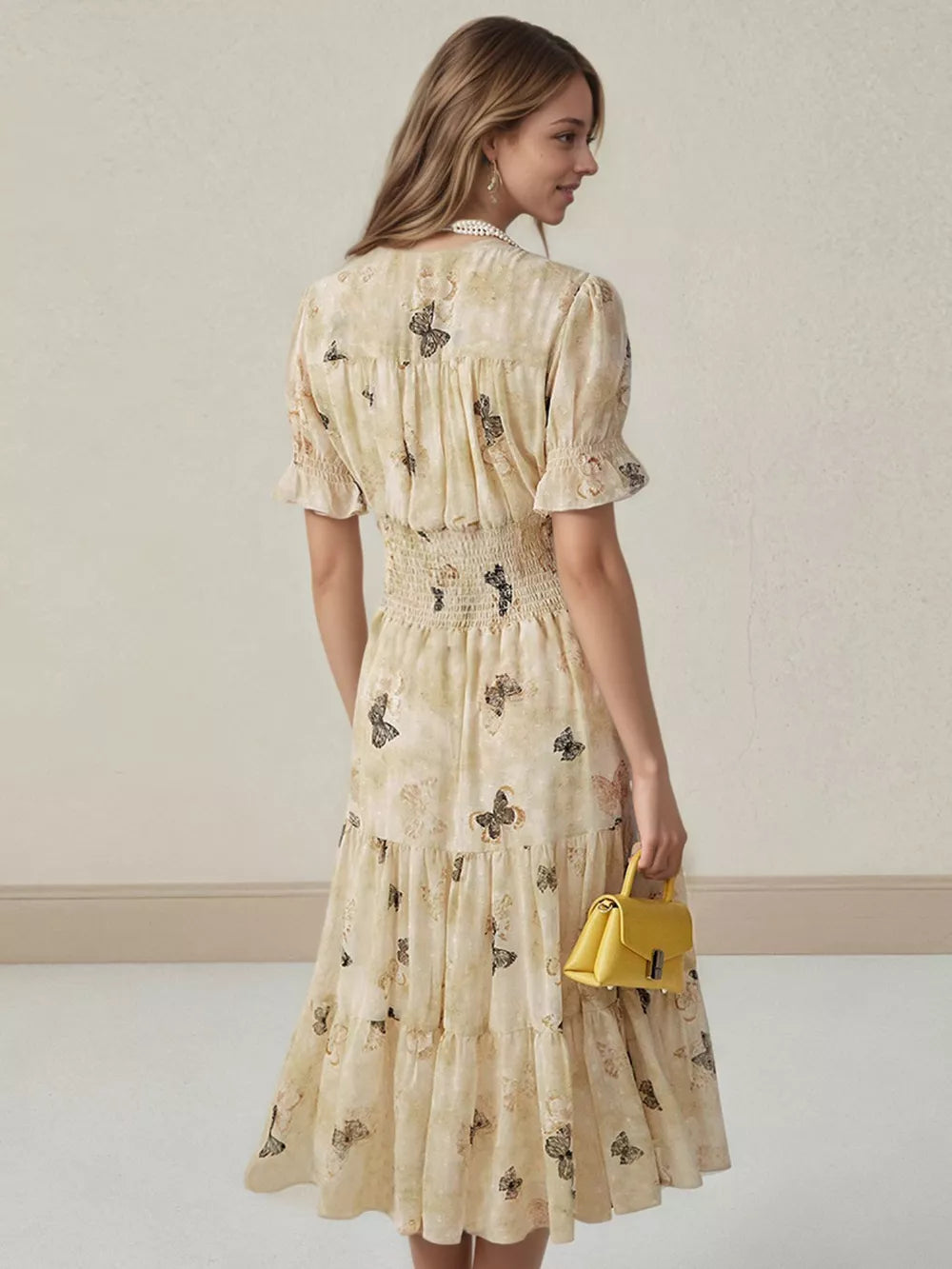 Beige butterfly print midi dress with smocked waist, ruffled sleeves, and tiered skirt.