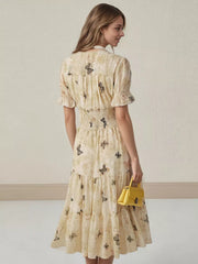 Beige butterfly print midi dress with smocked waist, ruffled sleeves, and tiered skirt.