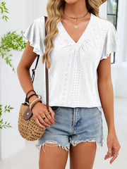 White eyelet flutter sleeve t-shirt with ruched V-neck, styled with denim shorts and a straw bag.