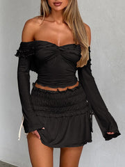 Black off-shoulder ruched bodice top with ruffled trim and long sleeves.