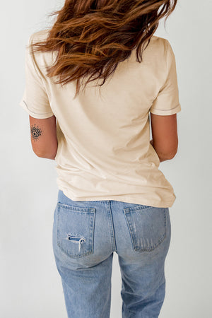 Light apricot t-shirt with short sleeves and a crew neck, styled with distressed denim jeans.