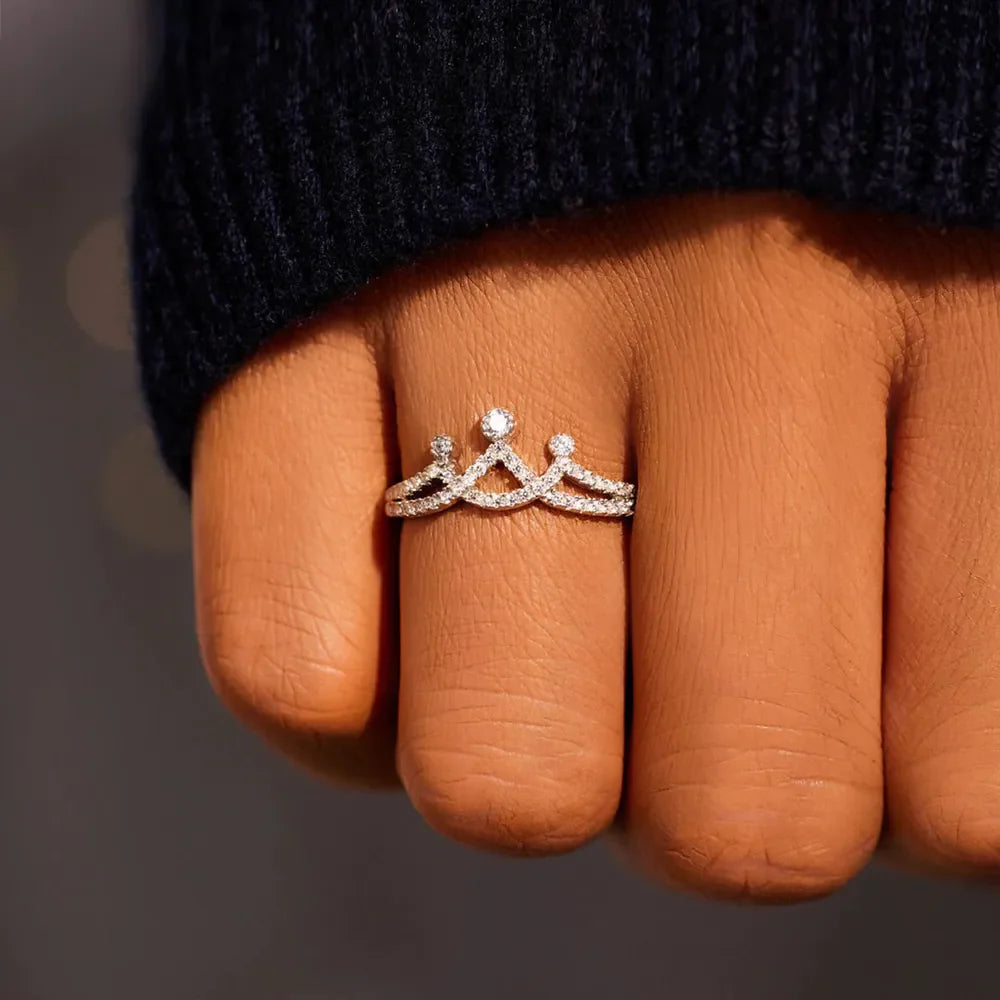Silver crown motif pave ring with small diamonds on a finger.