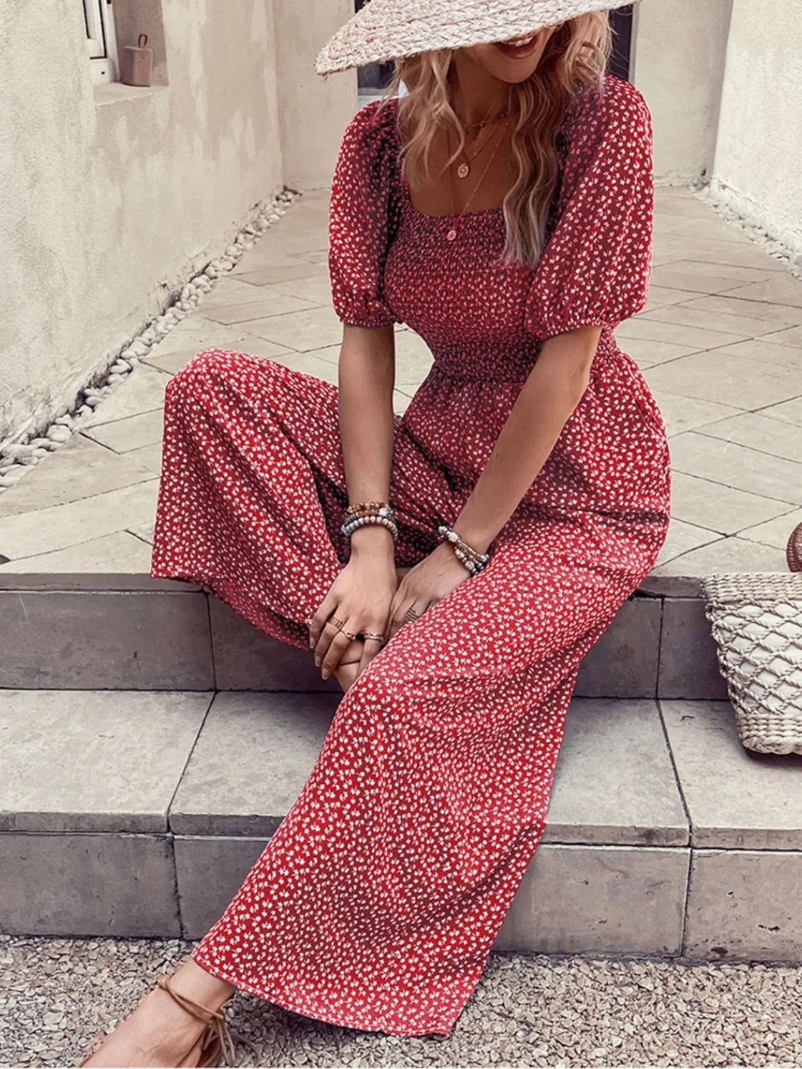 Red floral wide-leg jumpsuit with smocked bodice and puff sleeves.
