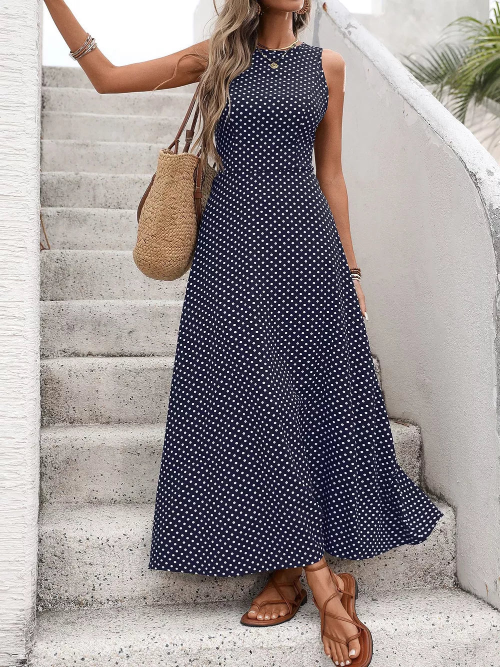 Dark blue polka dot maxi dress with a flattering silhouette, sleeveless, round neck, and flared skirt.