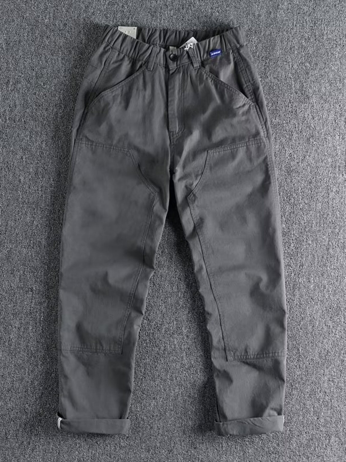 Men's grey elastic waist cargo pants with button closure and cuffed hems.