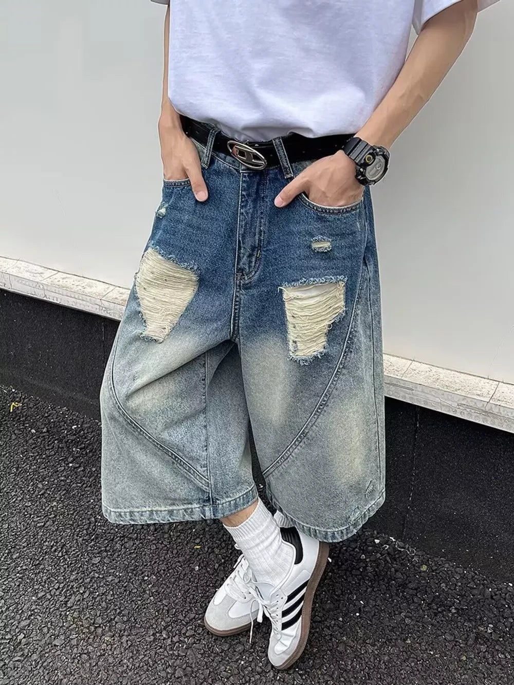 Men's distressed wide-leg denim shorts in light blue wash with ripped details.
