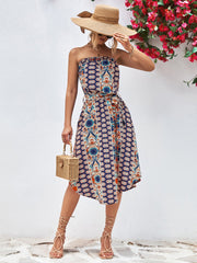 Printed bandeau midi dress with asymmetric hem and belt in dark blue with multicolor pattern.
