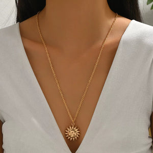 Gold sunburst pendant necklace with a detailed face on a delicate chain.