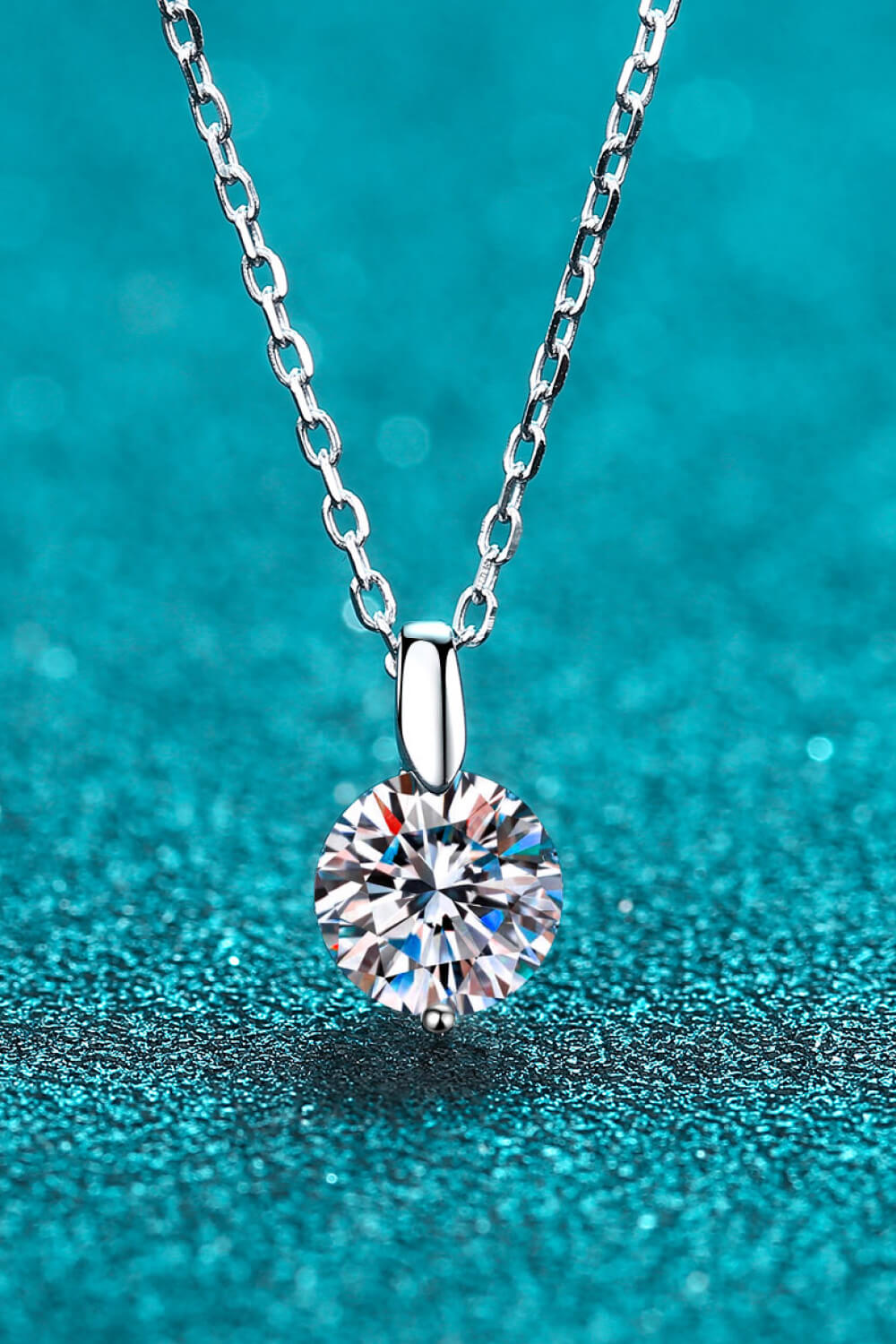 Silver solitaire moissanite pendant necklace with a round cut diamond.