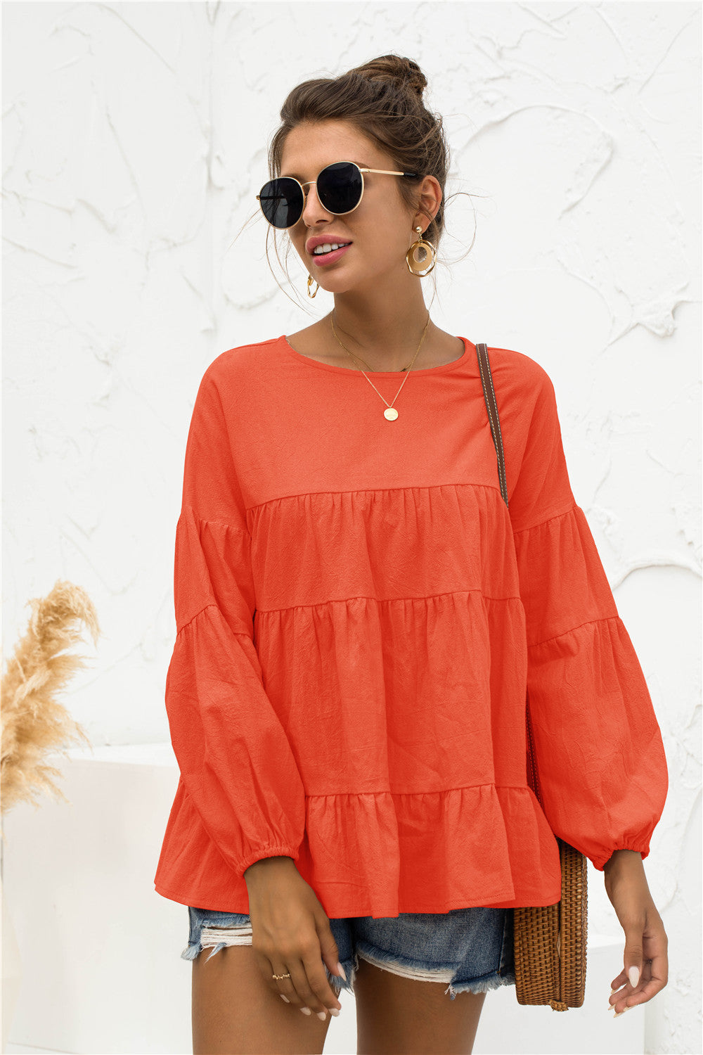 Orange tiered peasant blouse with ruffled balloon sleeves and a round neckline.