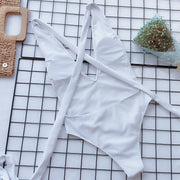 White wrap-around halterneck plunge swimsuit with crisscross straps and a high-cut leg.