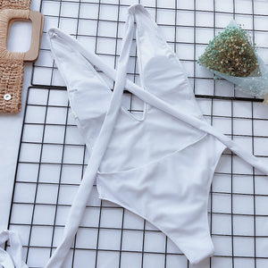 White wrap-around halterneck plunge swimsuit with crisscross straps and a high-cut leg.
