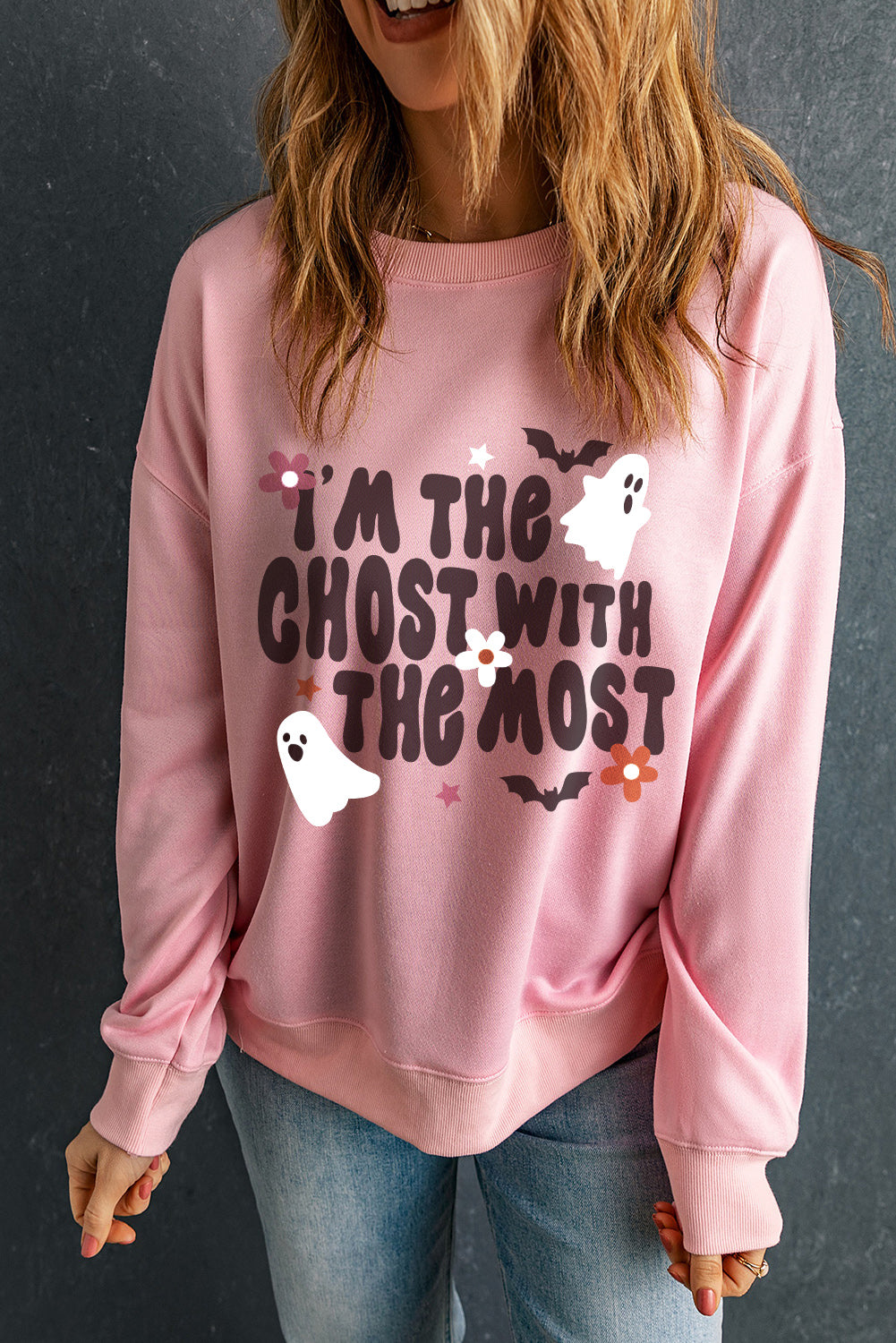 Blush pink crewneck sweatshirt with "I'm the ghost with the most" graphic, ghosts, bats, and flowers.