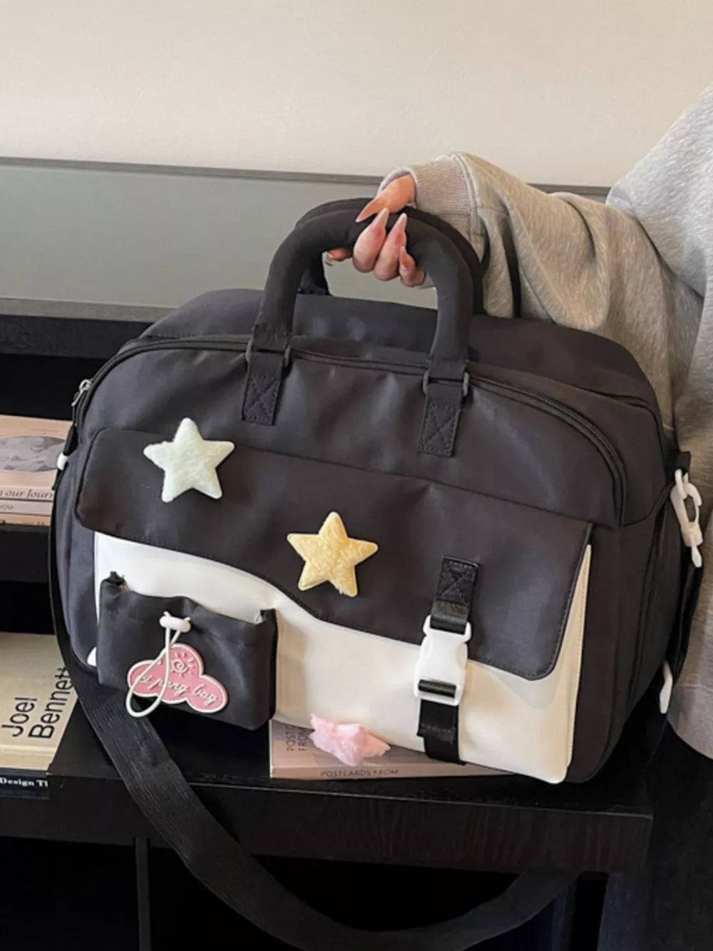 Chic color block travel bag in black and white with star embellishments and buckle details.