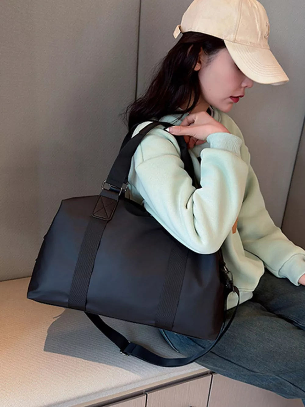 Sleek black Oxford cloth duffel bag with dual handles and adjustable shoulder strap.