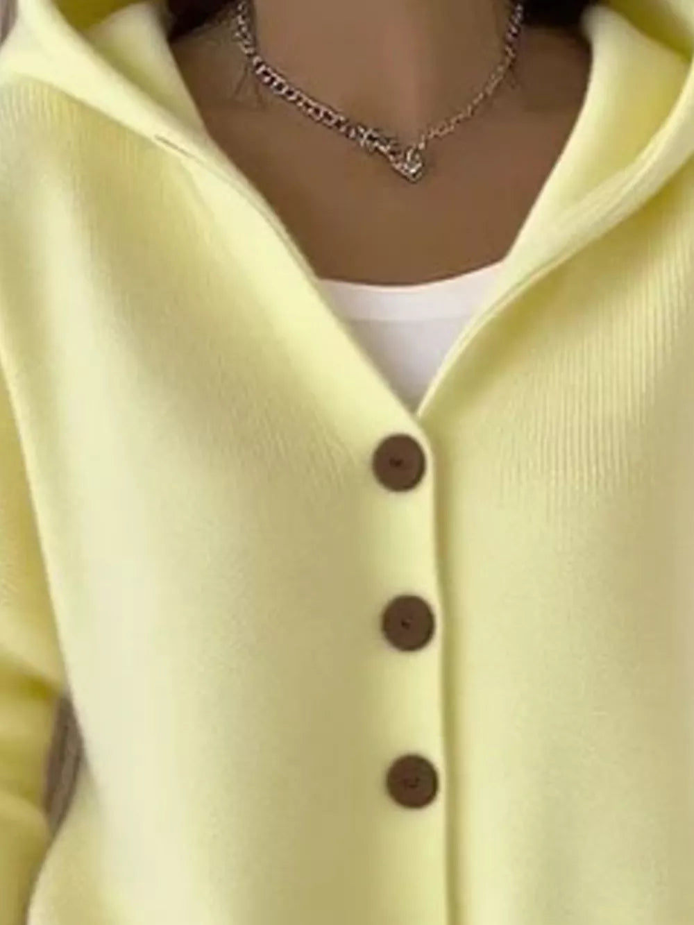 Yellow hooded knit cardigan with button front and white tank top.