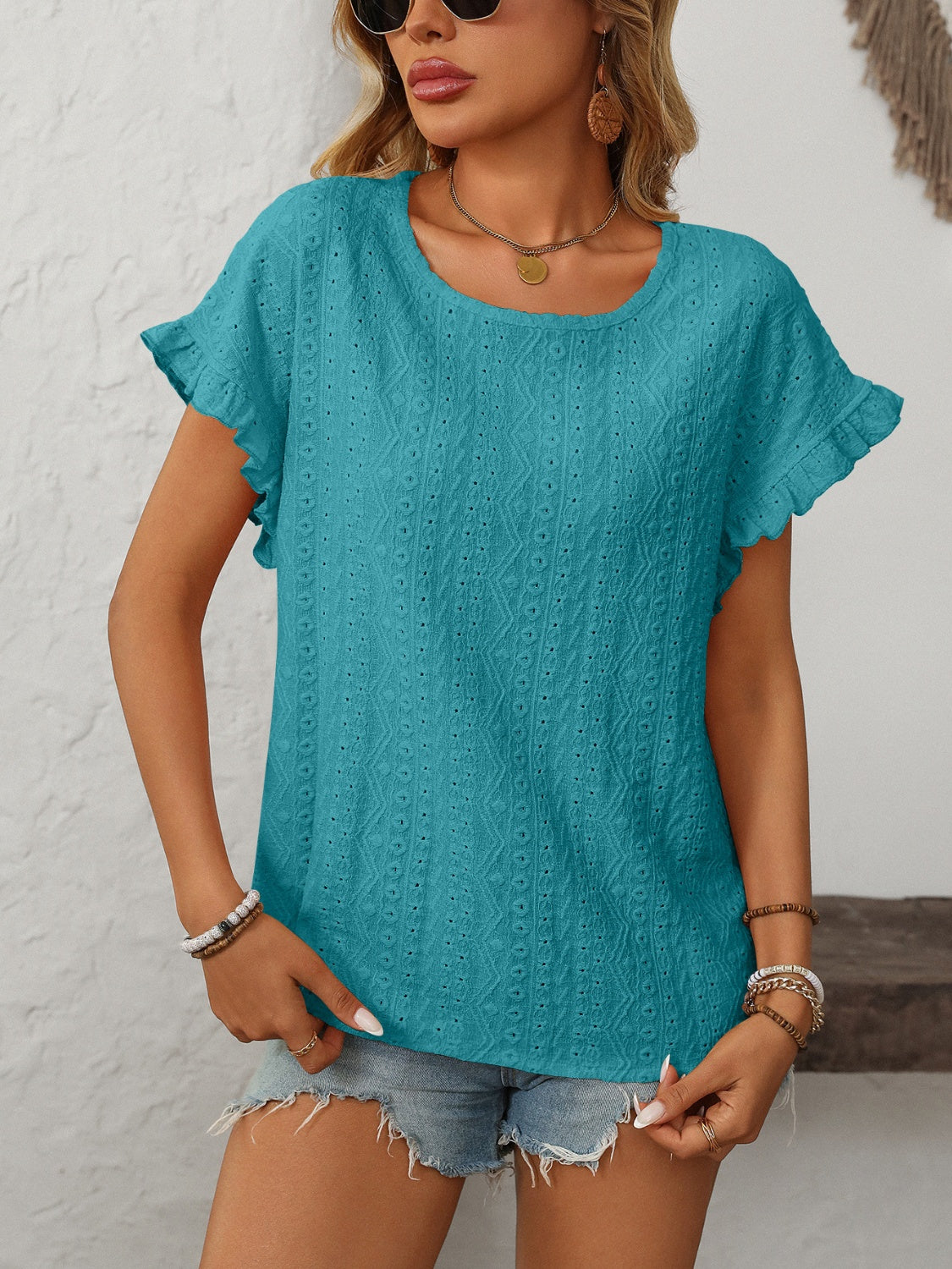 Teal eyelet knit blouse with ruffled short sleeves and a scoop neckline.